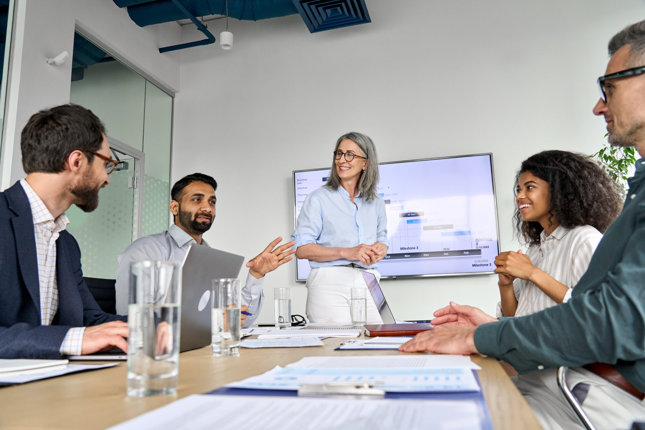 Diverse executive team people discussing company strategy at board meeting.