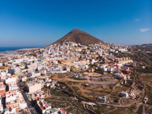 Drone view of small city of Galdar placed on Gran Canaria island with mountain peak under blue sky, Spain
